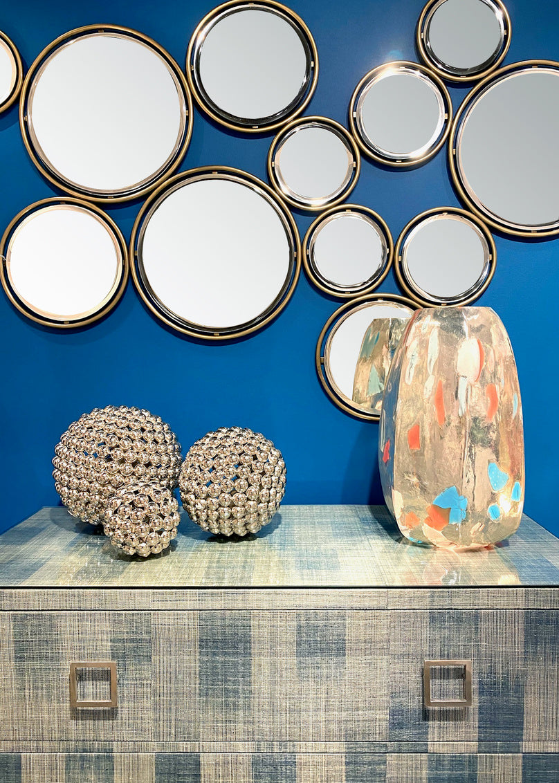 Decorative wall mirrors with a blue background and decorative vases on a shelf.