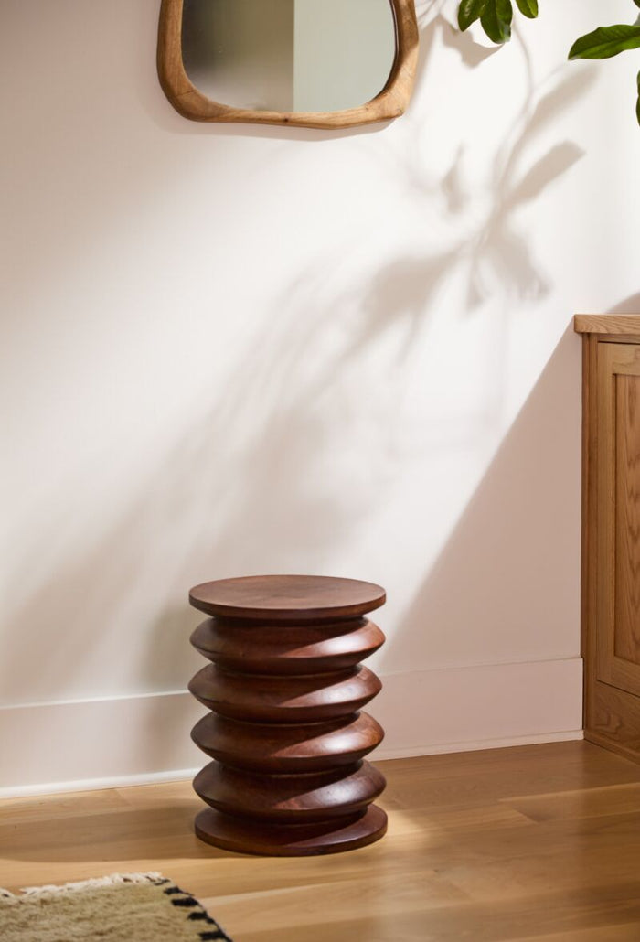 Wooden side table with a minimalist design against a light wall.