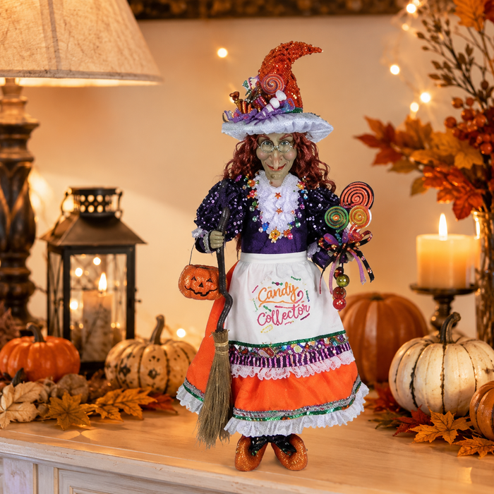 Halloween-themed doll with candy-themed outfit in a decorated room with pumpkins and candles.
