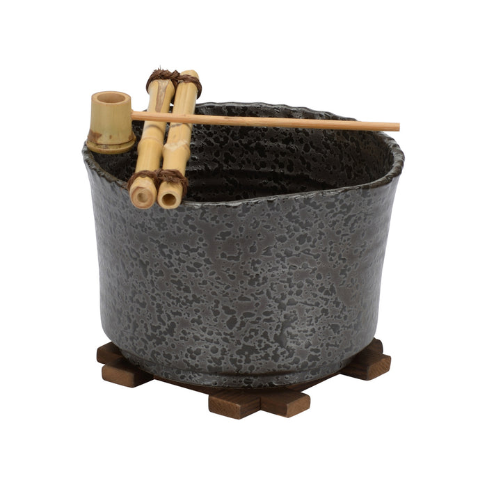 Ceramic pot with textured surface on a wooden stand, accompanied by bamboo sticks and skewers.