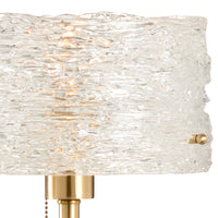 Lamp with textured glass shade and gold base on a white background