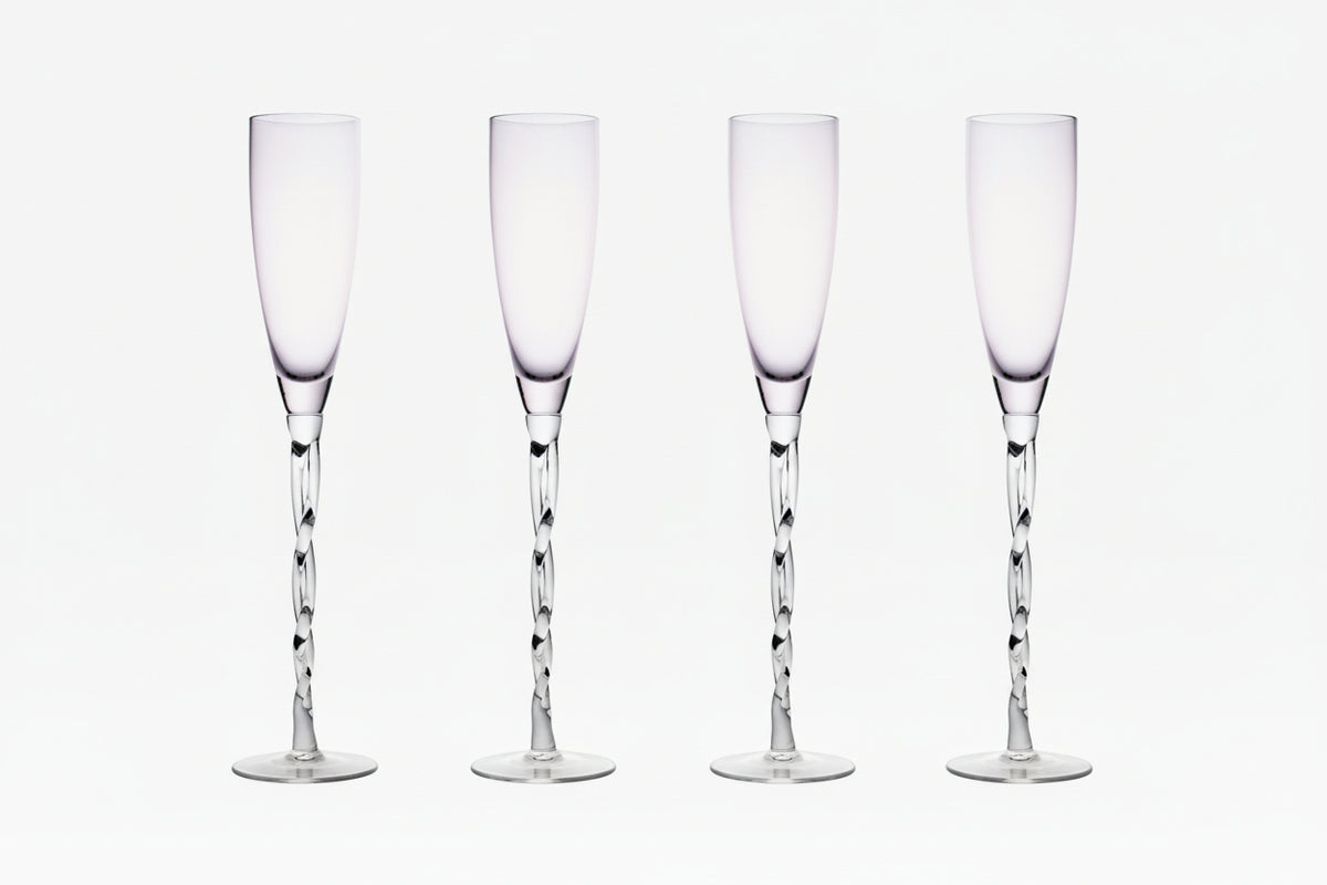 Set of four clear champagne flutes on a white background.
