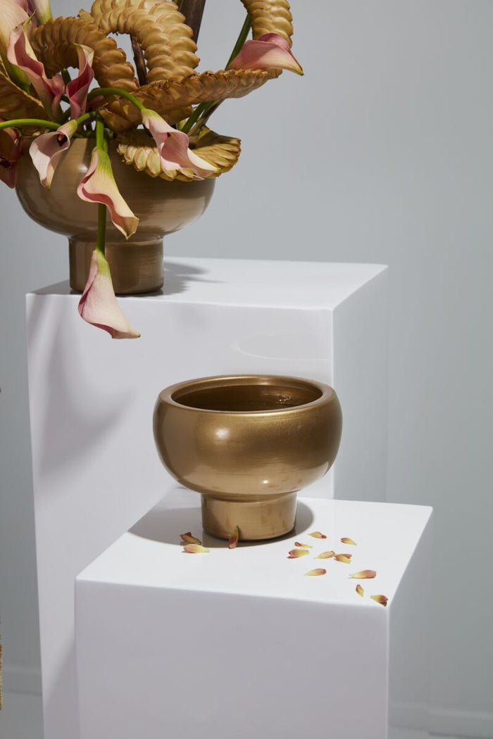 Bronze sculpture of a figure with a bowl on a white pedestal