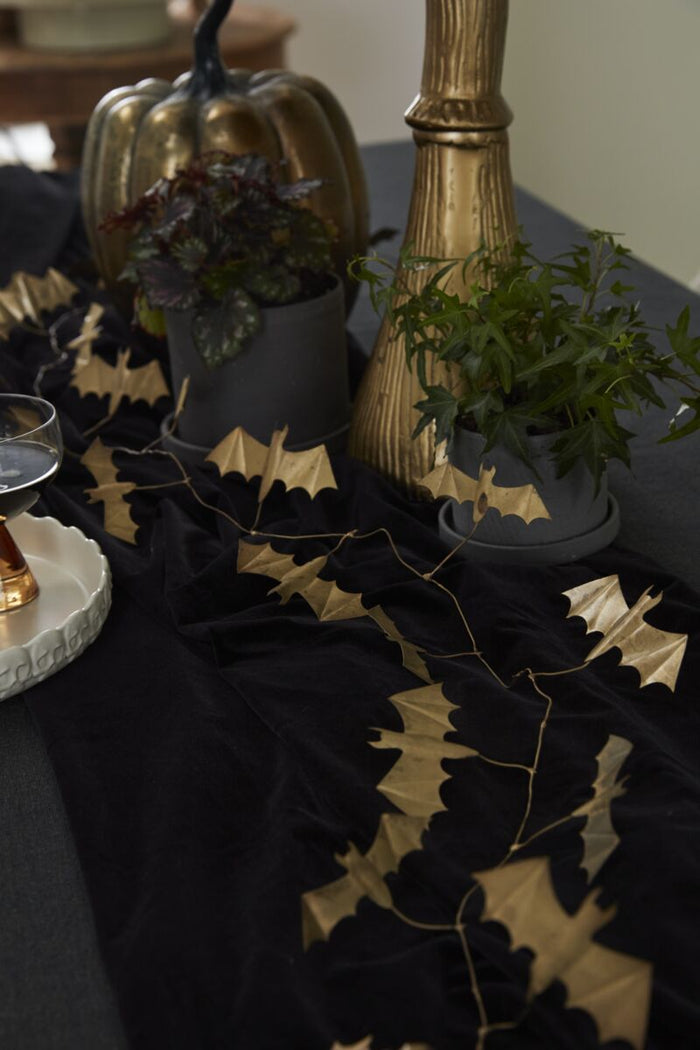 Decorative table setting with black bat-themed placemats on a white tablecloth.