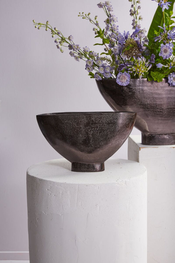 Dark brown first and second evolution vases with wide bowls, textured glaze, on white cylindrical pedestals; lavender stems