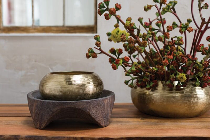 Two brass bowls on a wooden surface with a neutral background