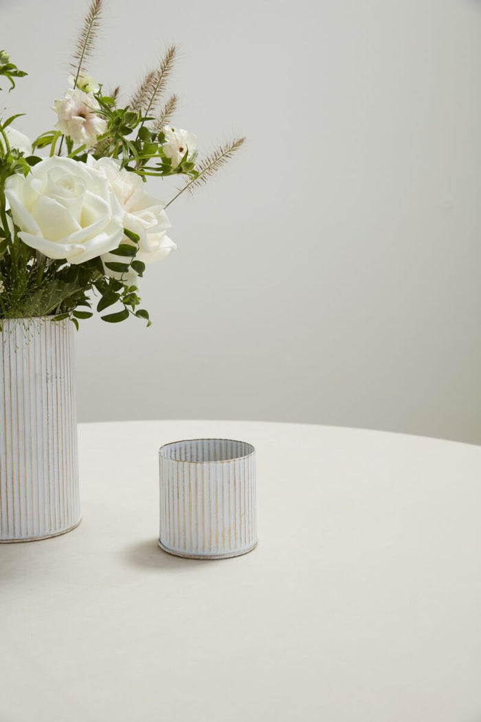 Two cylindrical vases with floral arrangements on a light surface and background