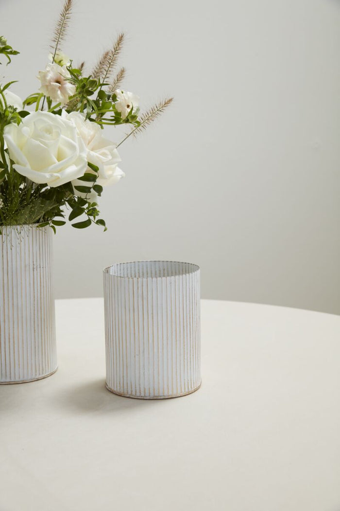 Two white ceramic vases with flowers on a light gray surface