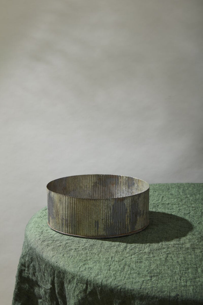 Design Shop Silver Norah Collection bowl, round, ribbed metal with a tarnished silver finish on a green fabric-covered table