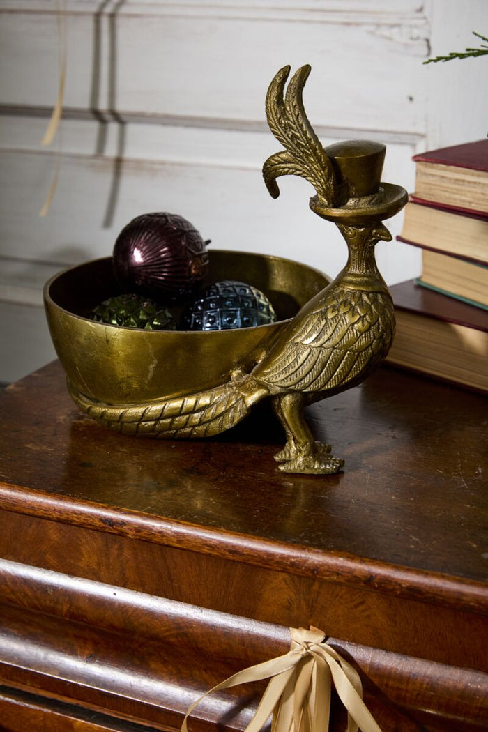 Brass bird-shaped container with decorative items on a wooden surface