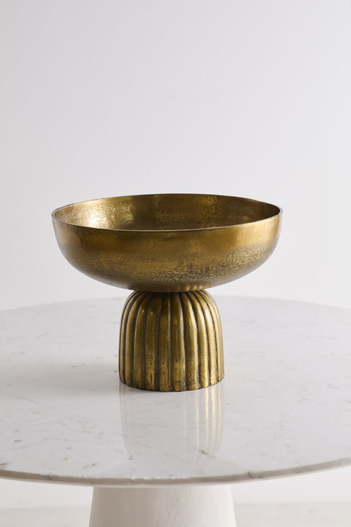 Brass bowl with ribbed base on a white surface