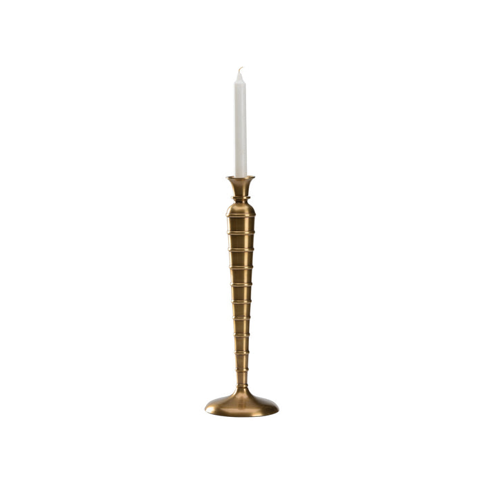 Brass candlestick holder with a white candle on a white background