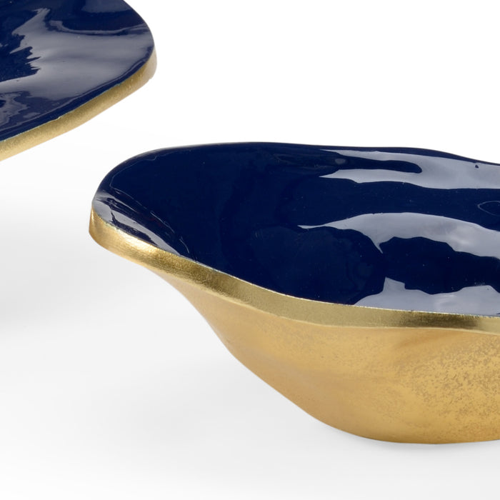 Decorative dish with blue and white abstract design on a gold rim against a white background