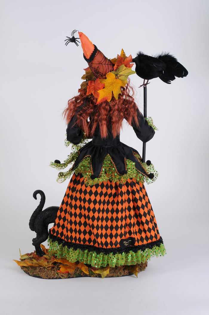 Halloween-themed doll with black cats, orange and green dress, and decorative elements on a white background