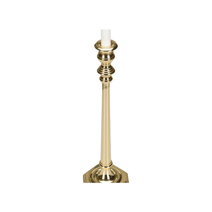 Gold candlestick holder with a white candle on a white background