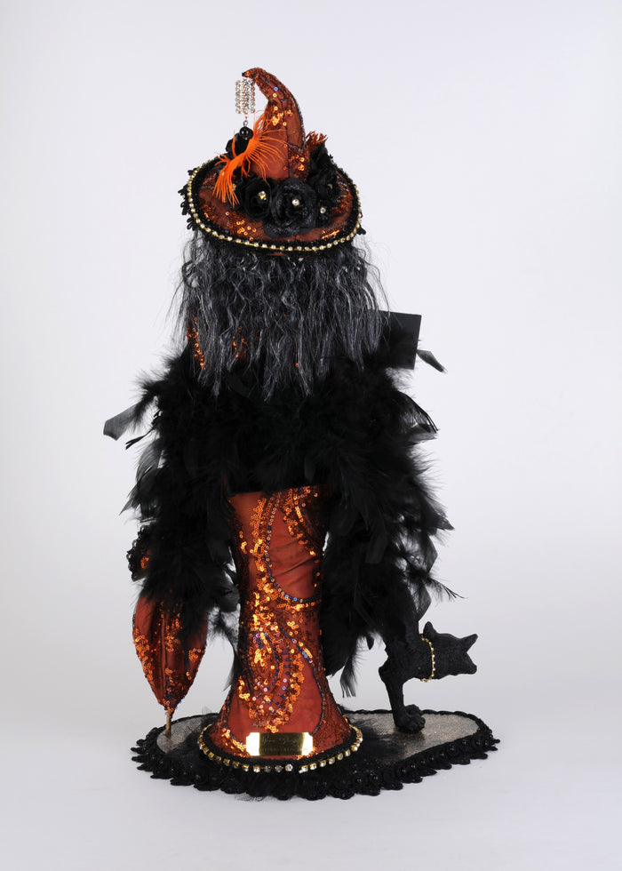 Decorative figure with black feathers and orange sequins on a white background