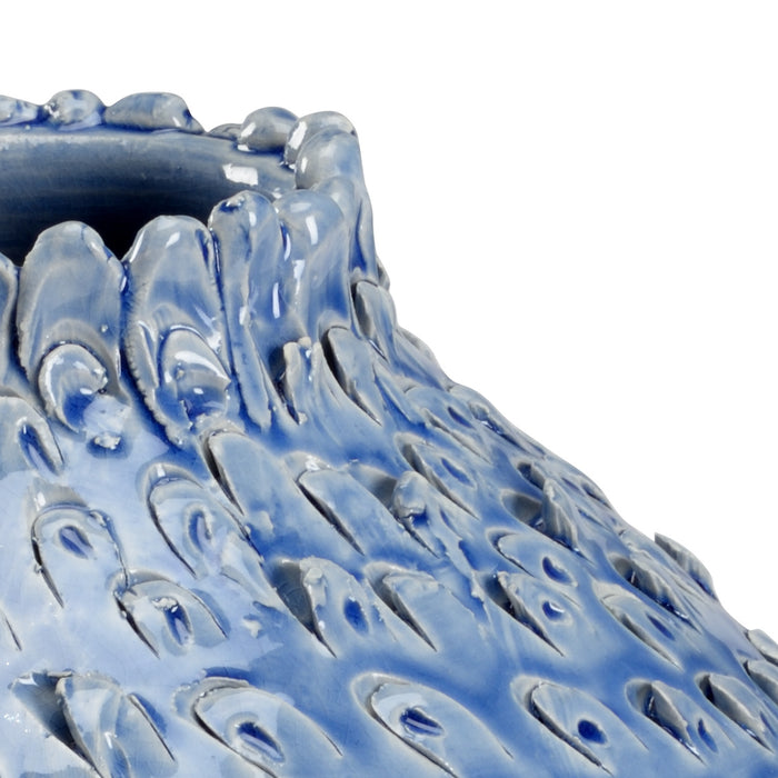 Close-up of a blue ceramic vase with textured design on a white background