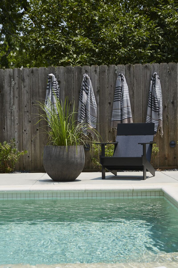 Chair by a pool with a wooden fence and plants in the background