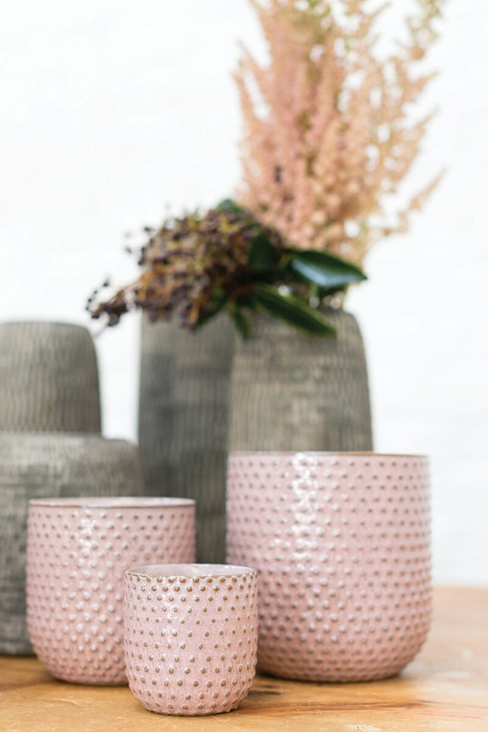 Set of ceramic pots with textured surfaces on a wooden surface