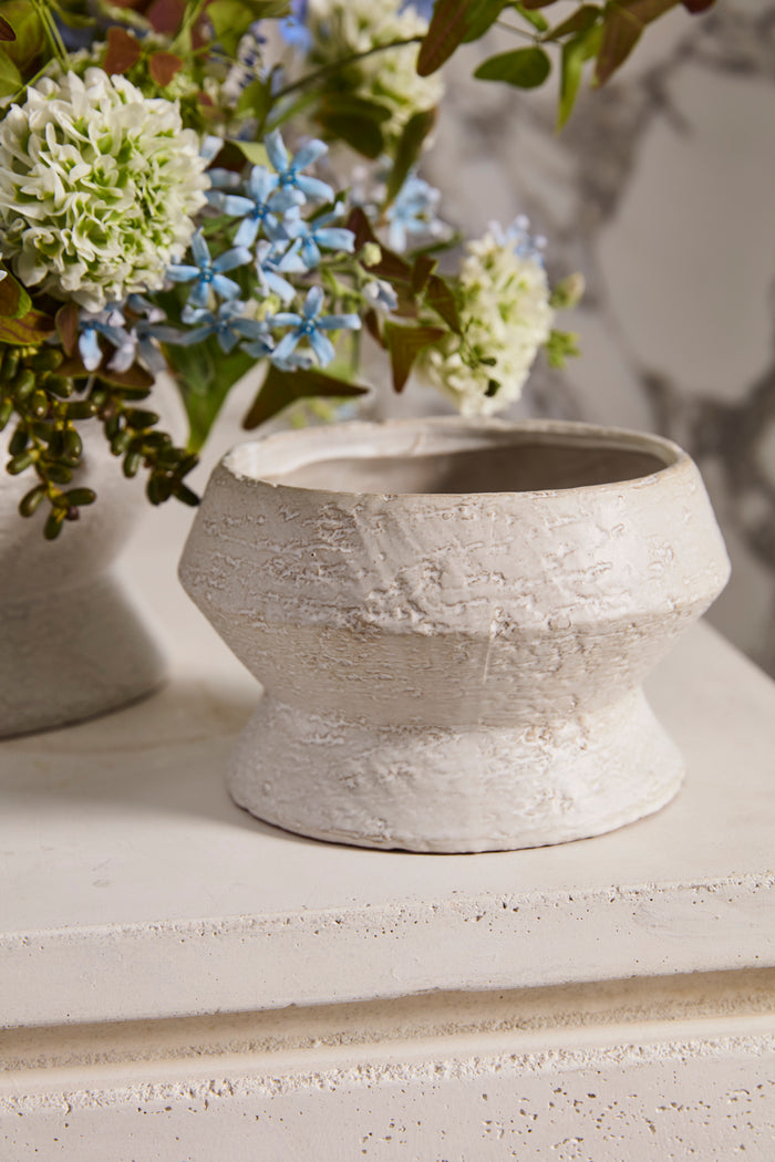 White textured vase with flowers on a light surface