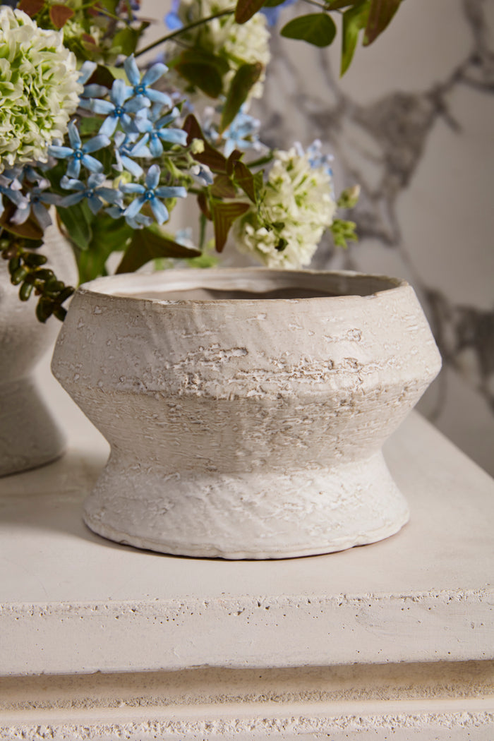 Decorative stone vase with flowers on a textured surface