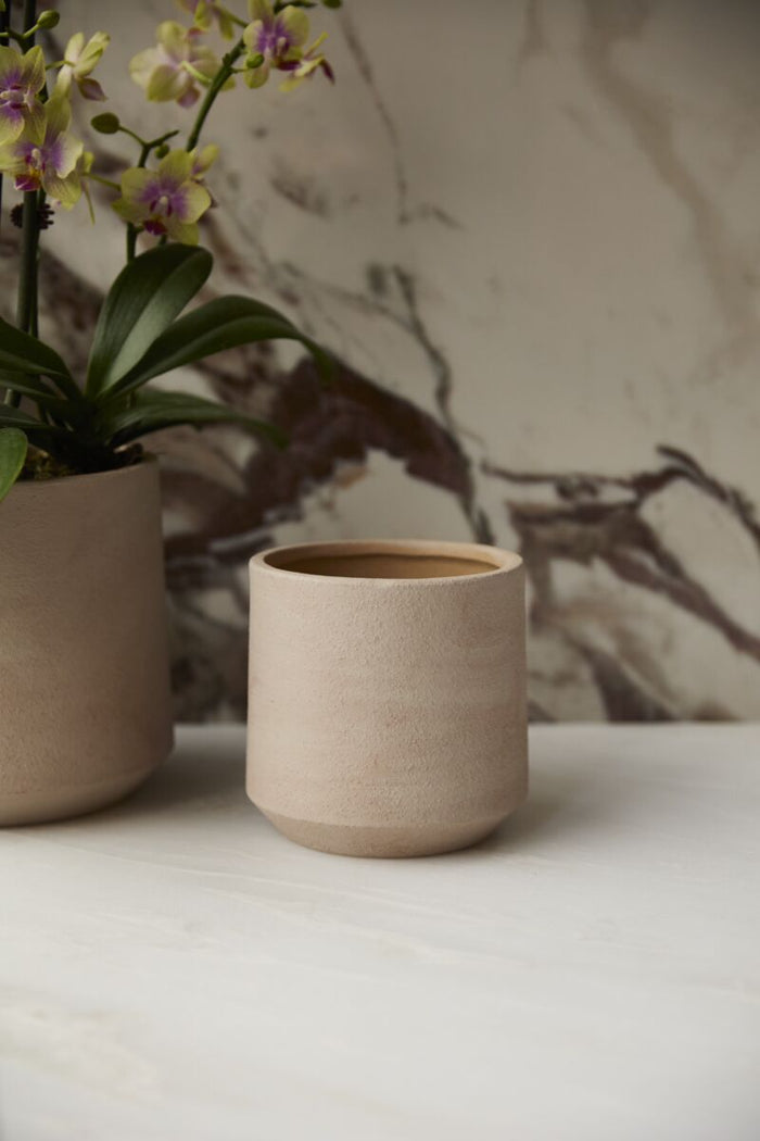 Beige ceramic cup on a white surface with a blurred background