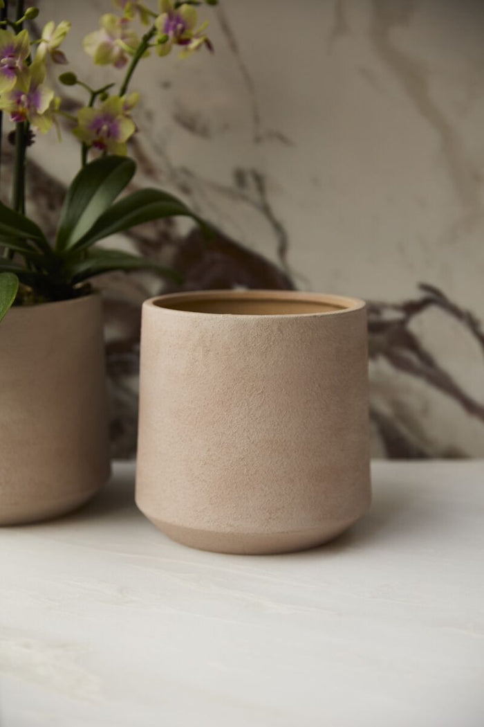 Beige ceramic cup on a white surface with a blurred background