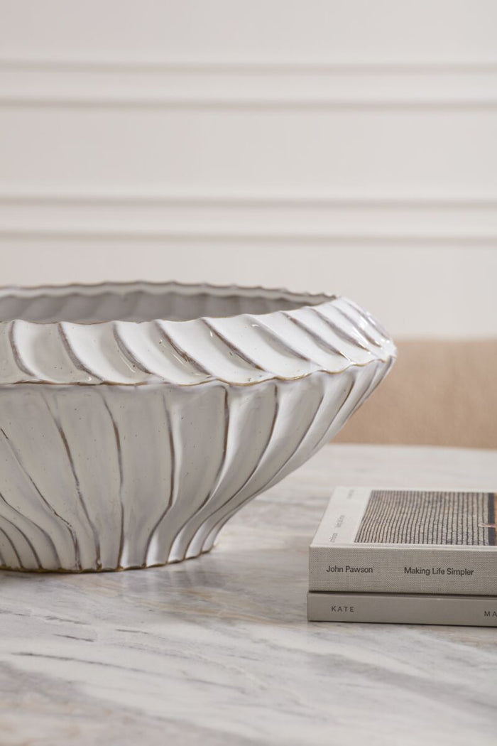 Decorative ceramic bowl on a surface with books in the background