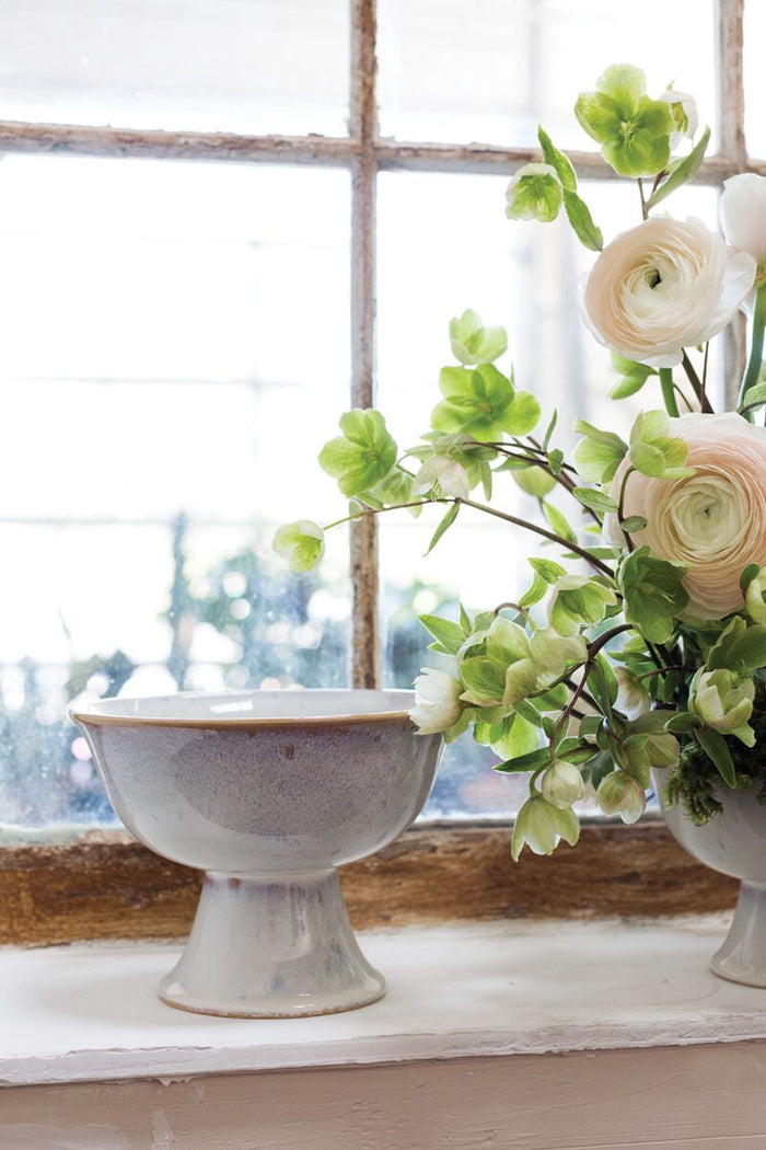 Two ceramic bowls with flowers on a windowsill