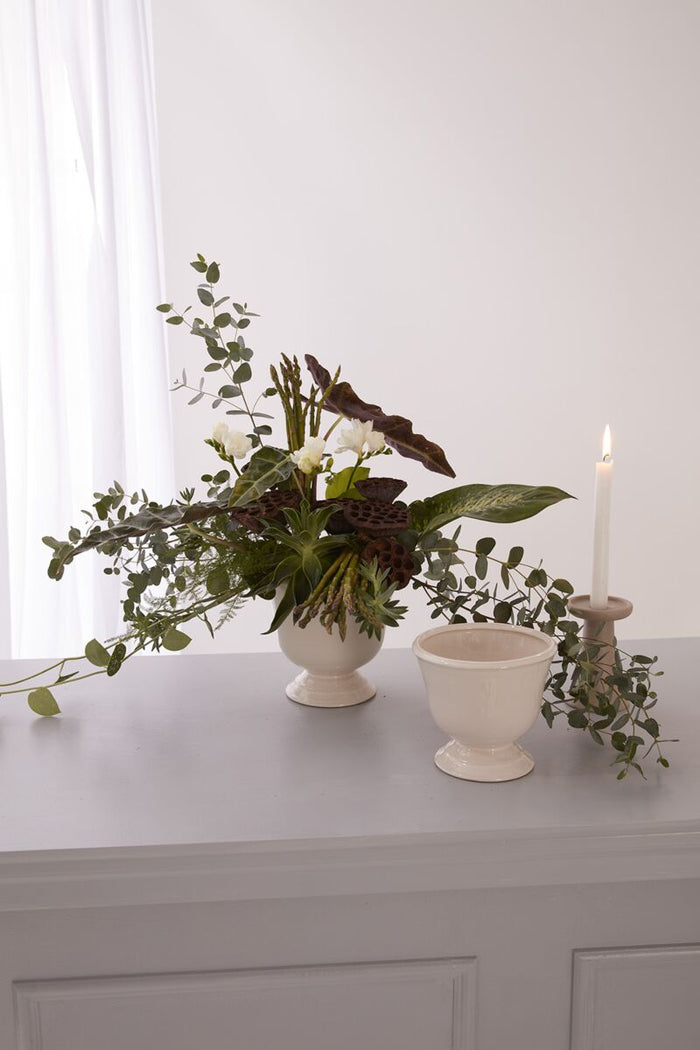 Floral arrangement in a white vase on a gray surface with a white background