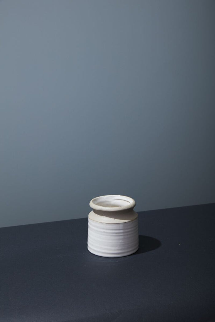 White ceramic vase on a dark surface with a gray background