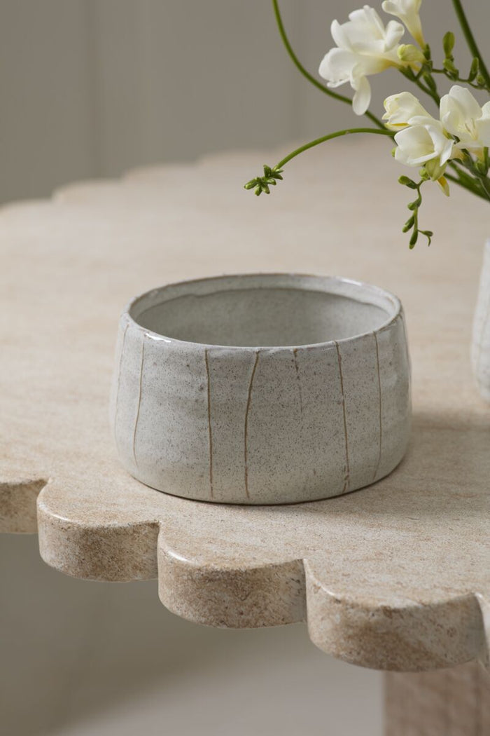 Gray textured bowl on a wooden stand with a blurred background