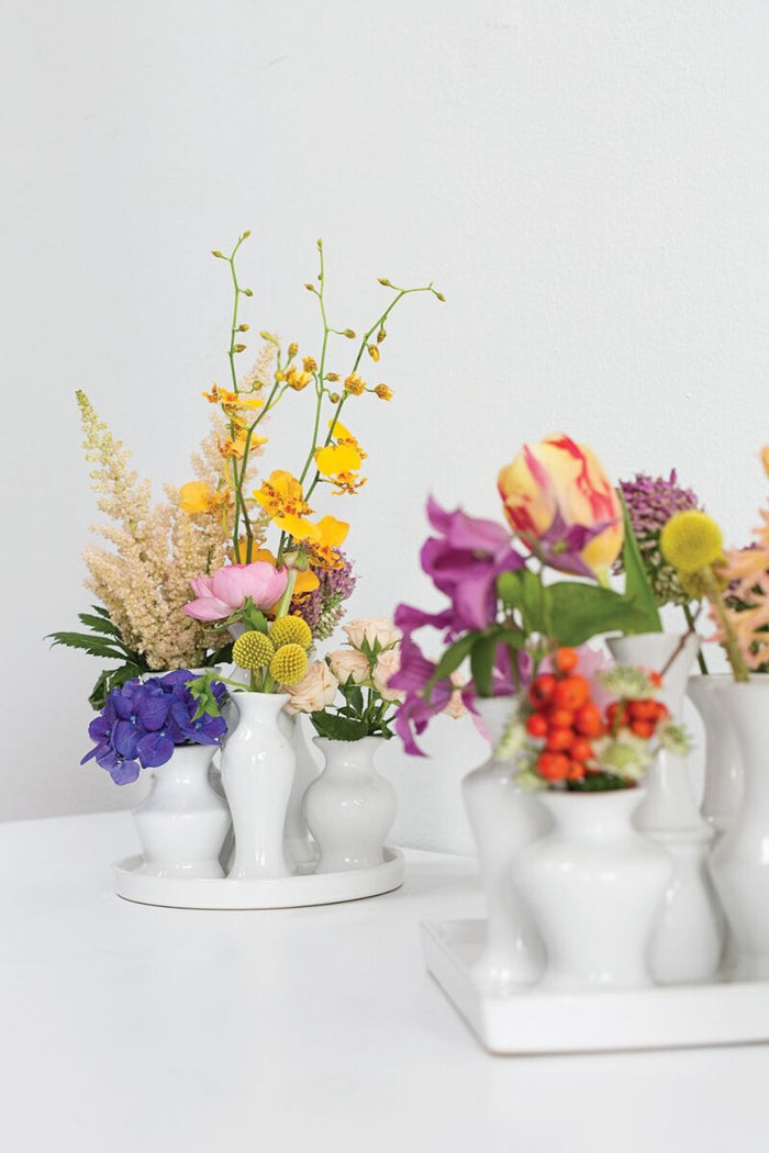 Colorful flower arrangements in white vases on a light background