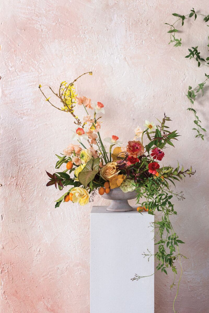Floral arrangement on a white surface with a light pink background
