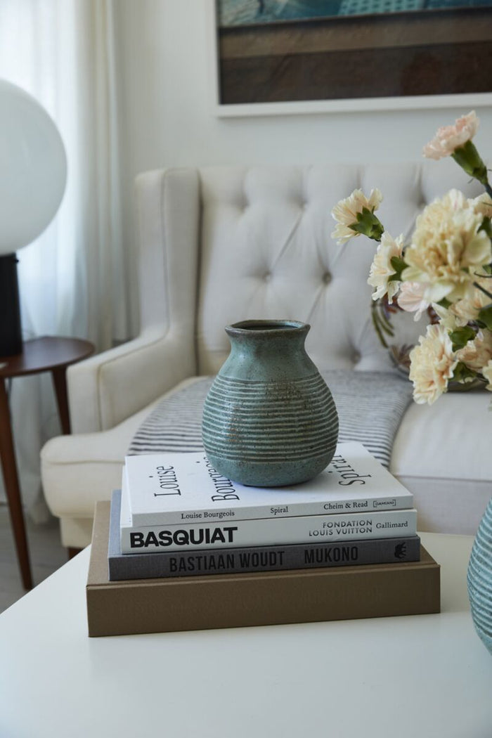 Teal vase on a stack of books with flowers in the background