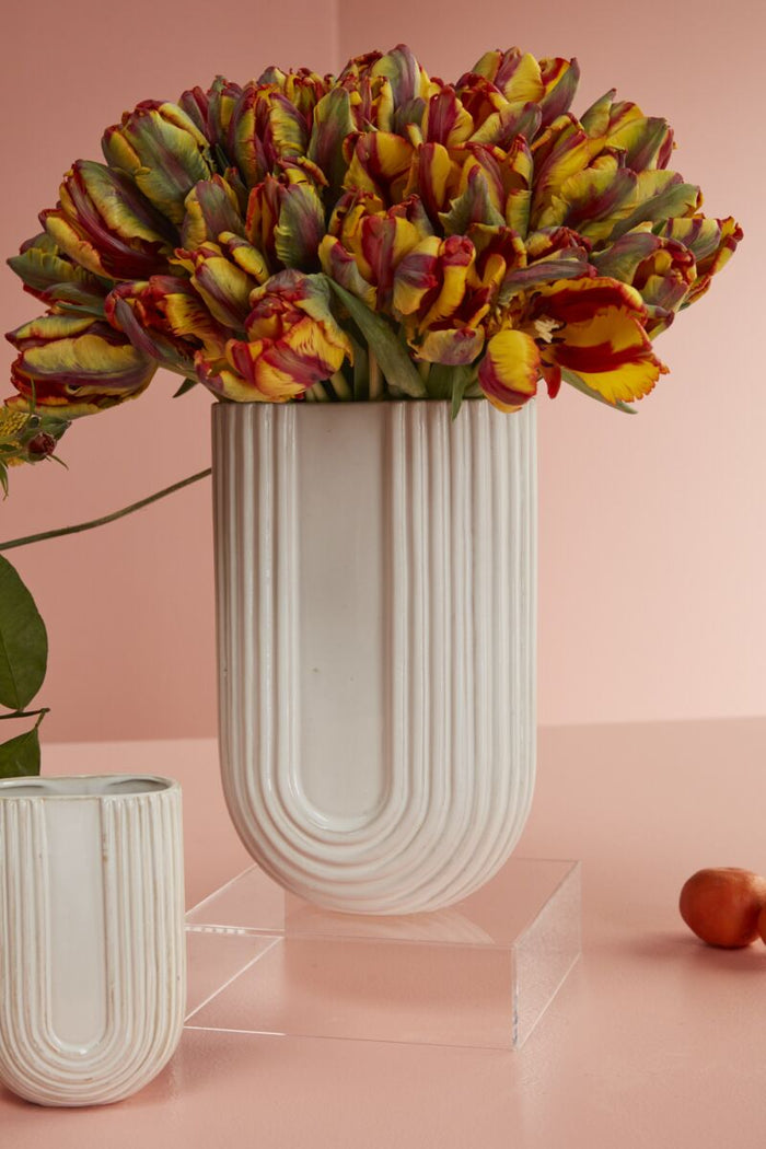 Decorative vase with colorful flowers on a pink background