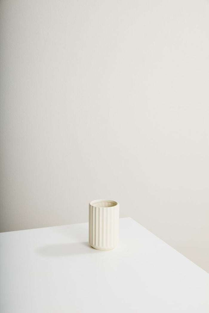 White ceramic vase on a white surface with a plain background