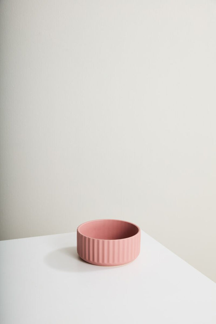 Pink ceramic bowl on a white surface with a light gray background