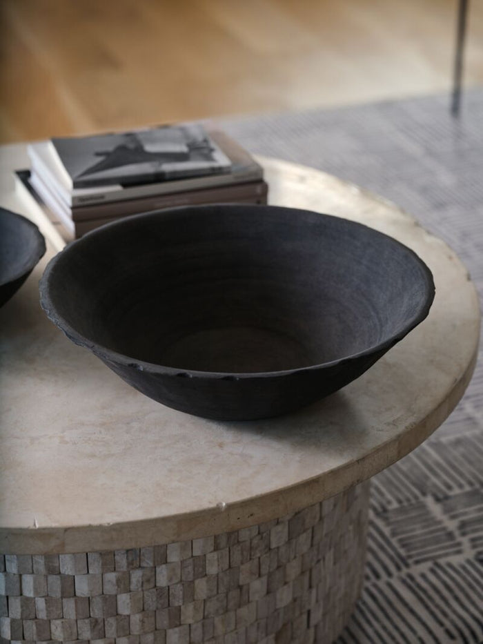 Black ceramic bowl on a round stone table with blurred background