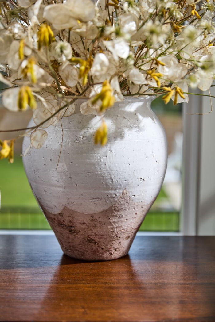 White textured vase with flowers on a wooden surface