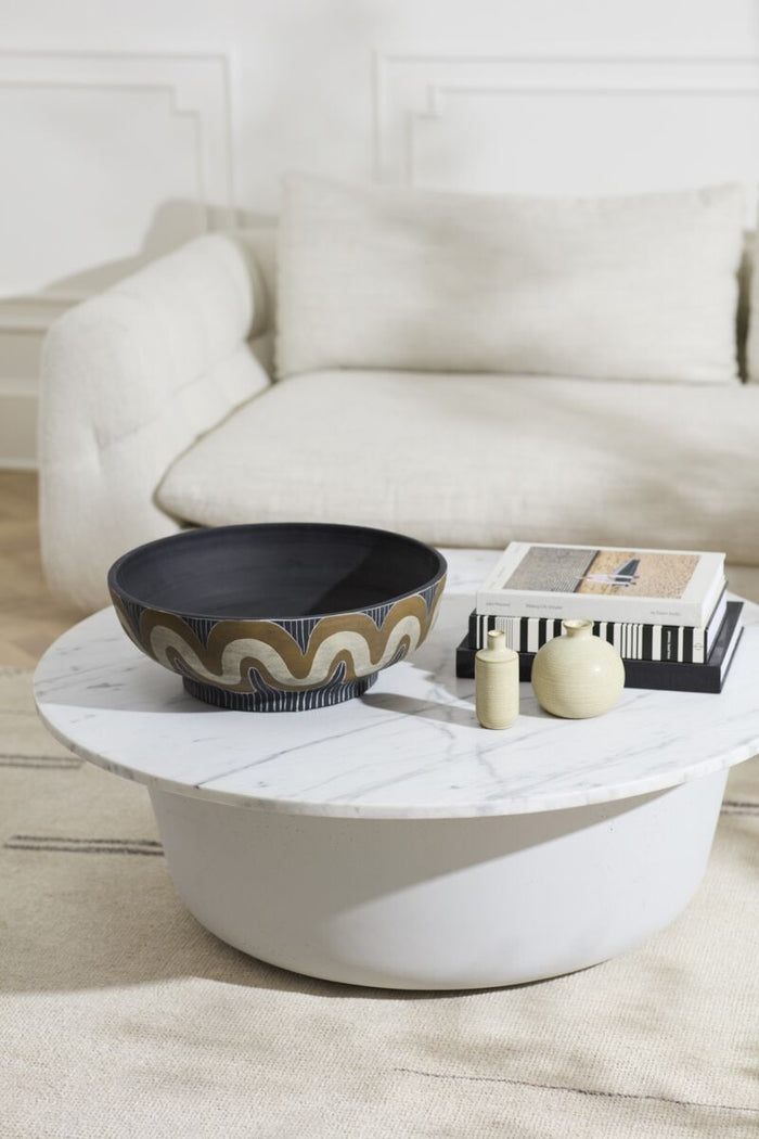 Modern living room with a white sofa, round coffee table, and decorative items.