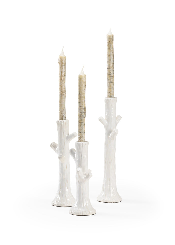 Set of three white candle holders with candles on a white background