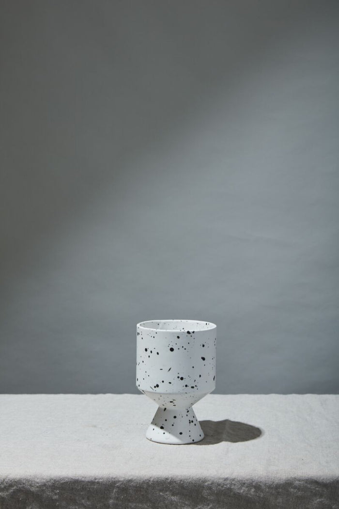 White terrazzo-style vase on a gray surface with a gray background