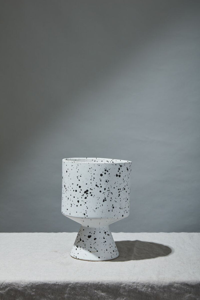 Speckled ceramic planter on a gray surface with a gray background