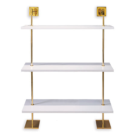 A modern multi-tier shelf with polished gold metal poles and white MDF wood shelves, designed to be secured to a wall.