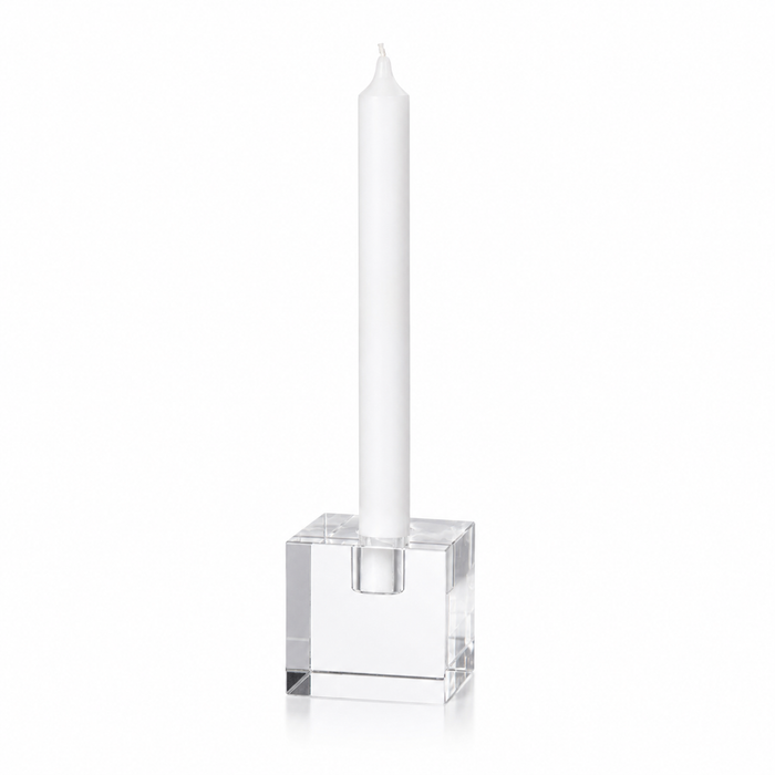 Clear glass candle holder with a white candle on a white background