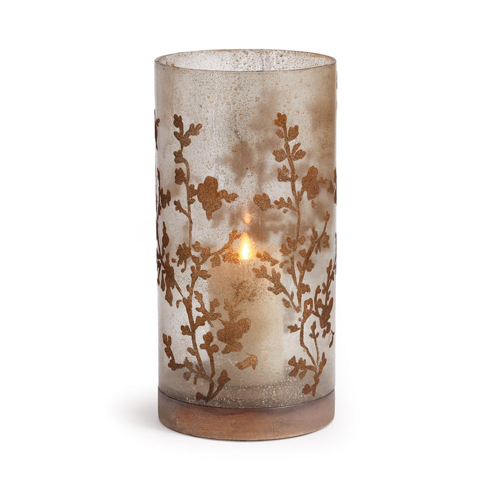 A medium-sized hurricane candle holder with a flowing vine motif on smoky glass, sitting atop a gray turned wood base.