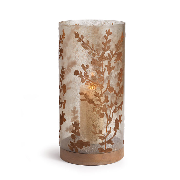A cylindrical glass hurricane with a floral vine motif design, sitting atop a gray wooden base.
