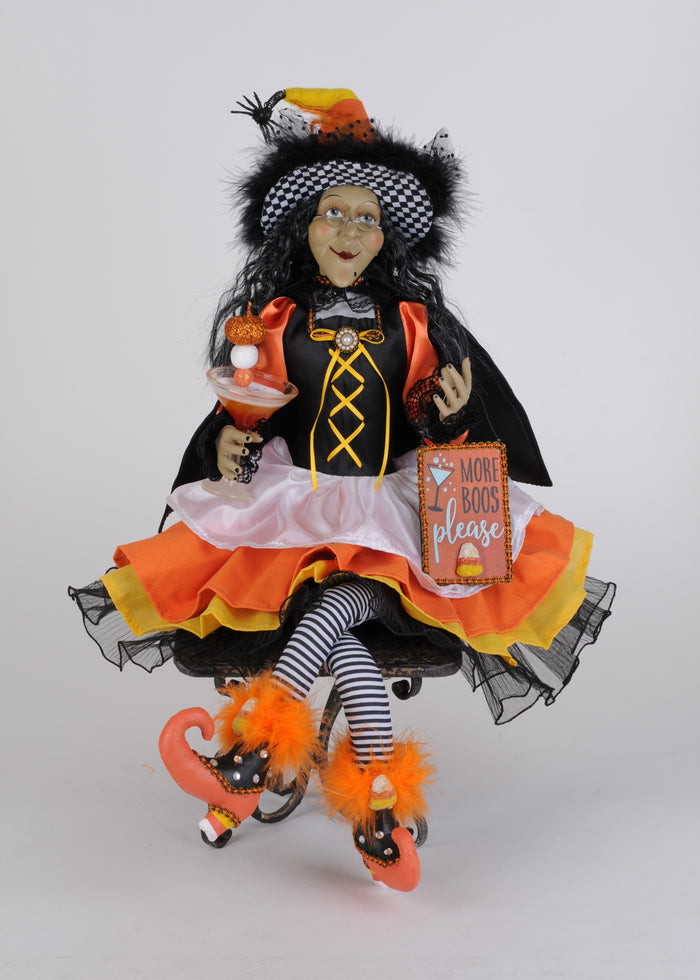 Halloween-themed doll in a black and orange outfit with striped stockings and candy shoes on a white background.