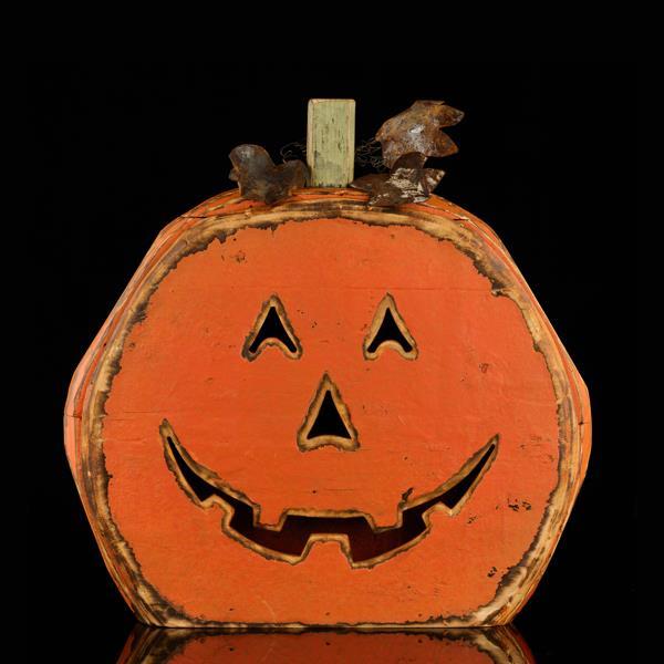 Wooden pumpkin decoration with a carved face on a black background